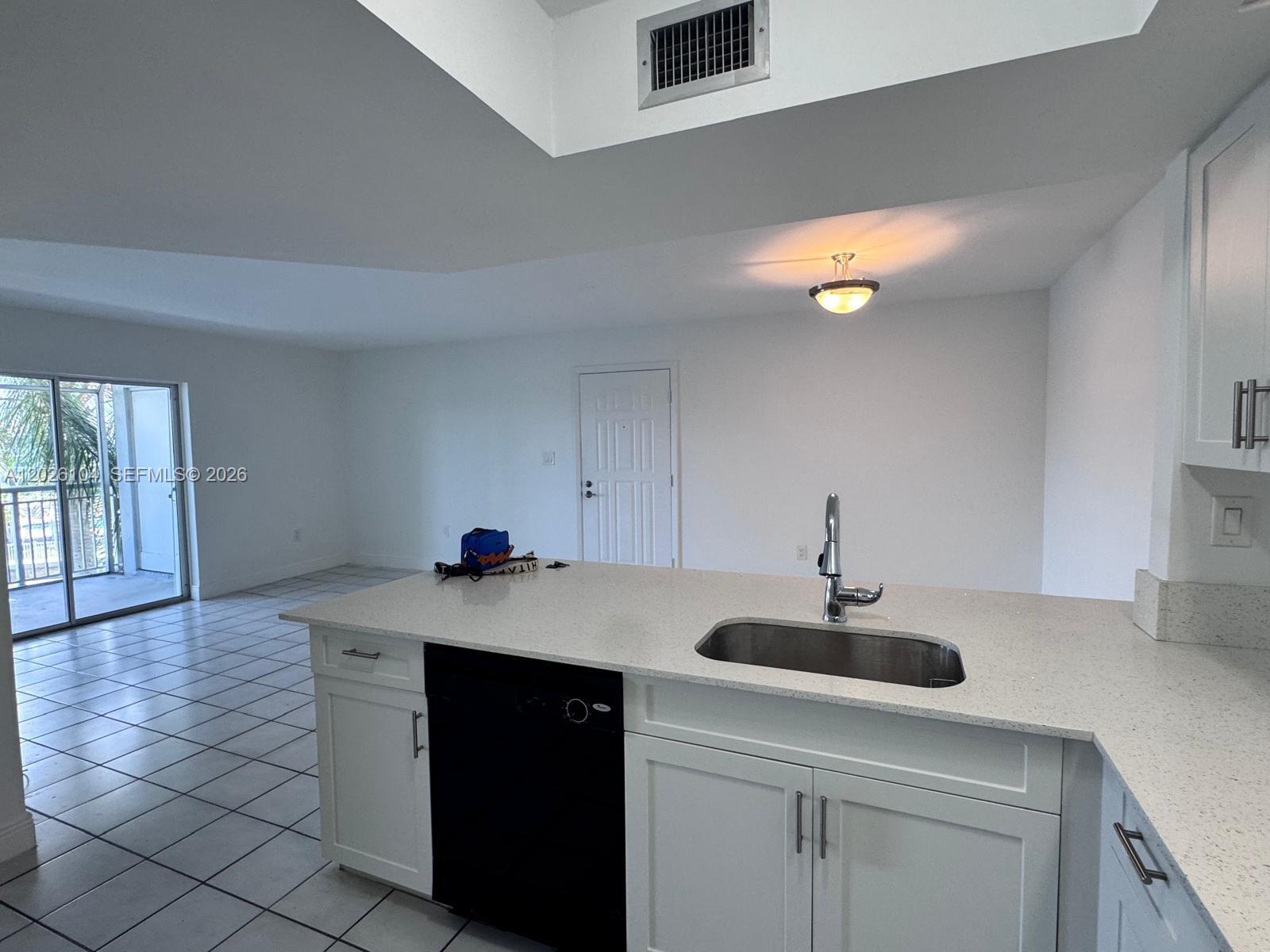 A kitchen island with a stainless steel sink faces a living area with tile floors — 8600 SW 212th St # 308, Cutler Bay FL 33189, CUTLER BAY, FL