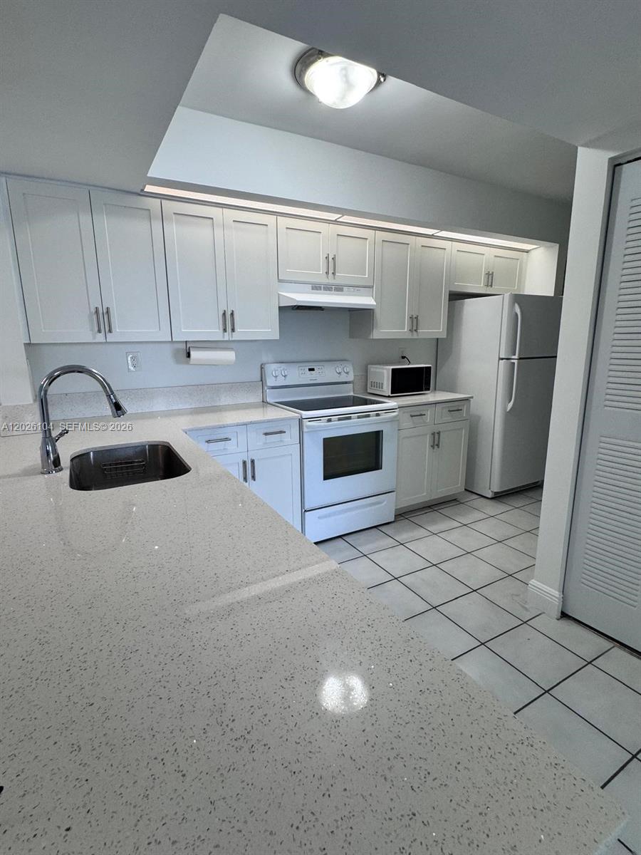 A kitchen features white cabinets, light-colored countertops, a stainless steel sink, and white appliances — 8600 SW 212th St # 308, Cutler Bay FL 33189, CUTLER BAY, FL