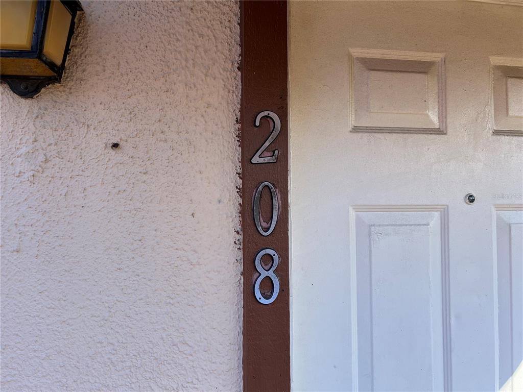 The house number 208 is mounted vertically on a brown door frame next to a door — 5026 WATER OAK DRIVE UNIT 208, BRADENTON, FL