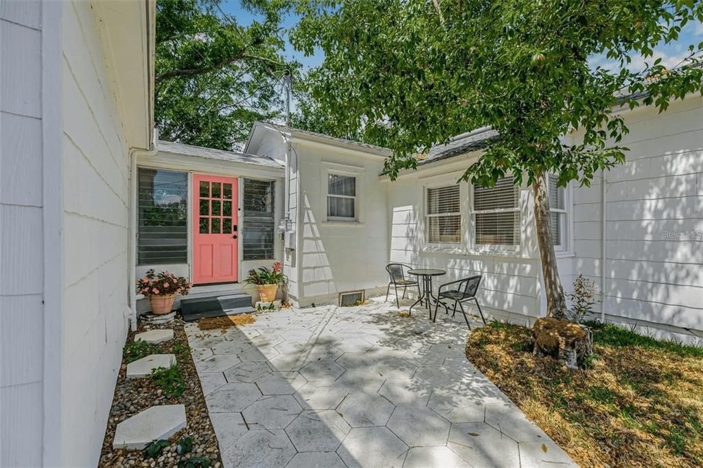 A white house exterior features a pink door, a stone patio, and a small tree — 3500 6TH AVENUE N, ST PETERSBURG, FL