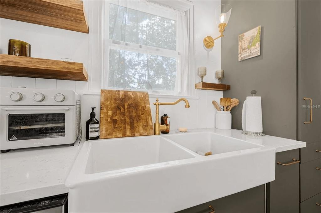 A kitchen sink area features a white farmhouse sink, gold faucet, and wooden shelving — 3500 6TH AVENUE N, ST PETERSBURG, FL