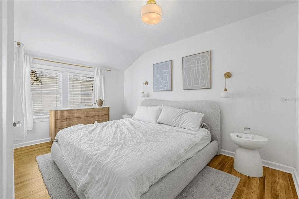 A bedroom features a light gray upholstered bed, two wall-mounted lamps, and a wooden dresser — 3500 6TH AVENUE N, ST PETERSBURG, FL