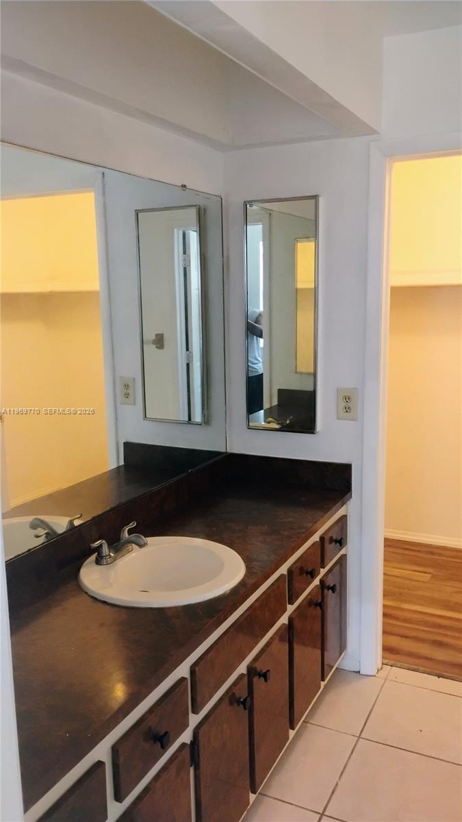 A bathroom vanity features a dark countertop, white sink, wood-toned cabinets, and multiple mirrors — 1404 SE 19TH St., Cape Coral FL 33990, CAPE CORAL, FL