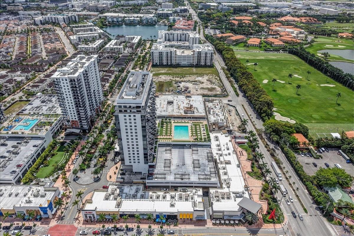 An aerial view shows a high-rise apartment building with a pool deck and adjacent construction — 5252 NW 85th Ave # 1410, Doral FL 33166, DORAL, FL