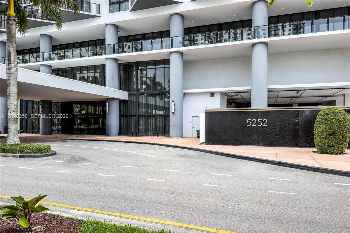 A modern building exterior features a covered driveway, large gray columns, and a numbered wall — 5252 NW 85th Ave # 1410, Doral FL 33166, DORAL, FL