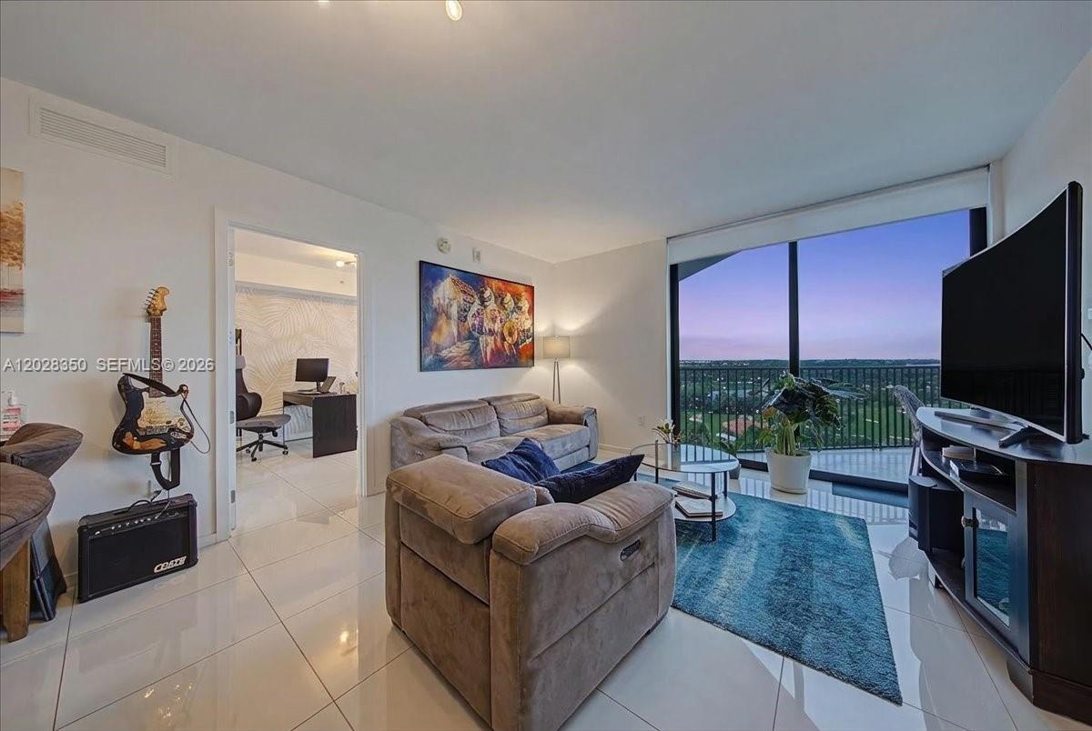 A living room features tile floors, a sofa, a television, and a balcony with views — 5252 NW 85th Ave # 1410, Doral FL 33166, DORAL, FL