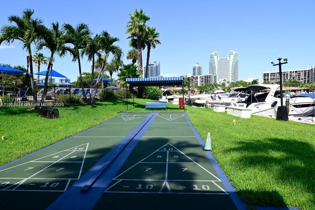 An outdoor shuffleboard court sits on a grassy lawn near a marina with boats — 500 Three Islands Blvd # 908, Hallandale Beach FL 33009, HALLANDALE BEACH, FL