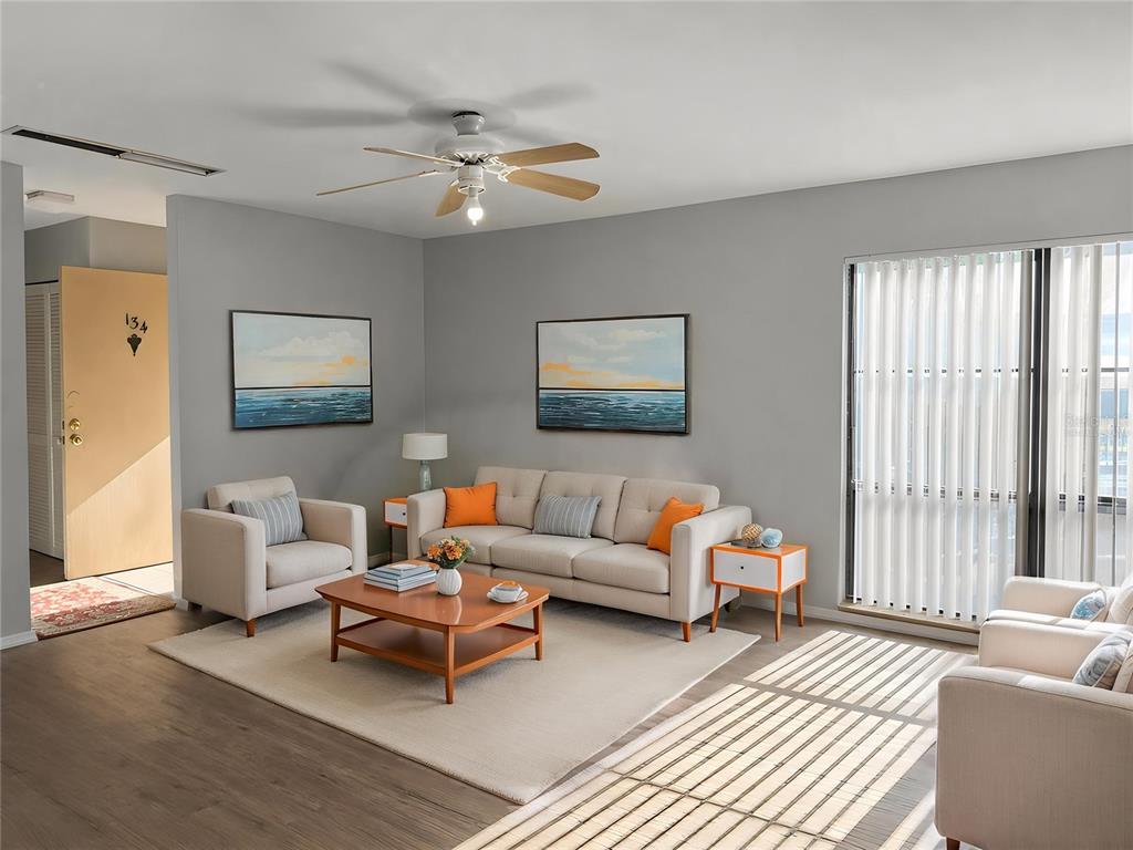 A living room features a sofa, armchairs, a coffee table, and two framed ocean paintings — 2811 SW ARCHER ROAD UNIT P134, GAINESVILLE, FL