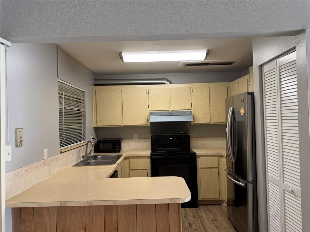 A kitchen features light-colored cabinets, a black stove, a stainless steel refrigerator, and laminate countertops — 2811 SW ARCHER ROAD UNIT P134, GAINESVILLE, FL