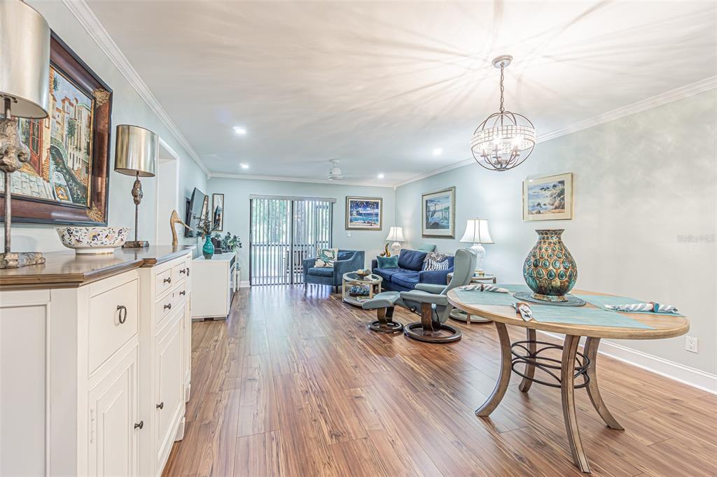 A living and dining room with wood-look flooring, blue furniture, and a round dining table — 3505 TARPON WOODS BOULEVARD UNIT G405, PALM HARBOR, FL