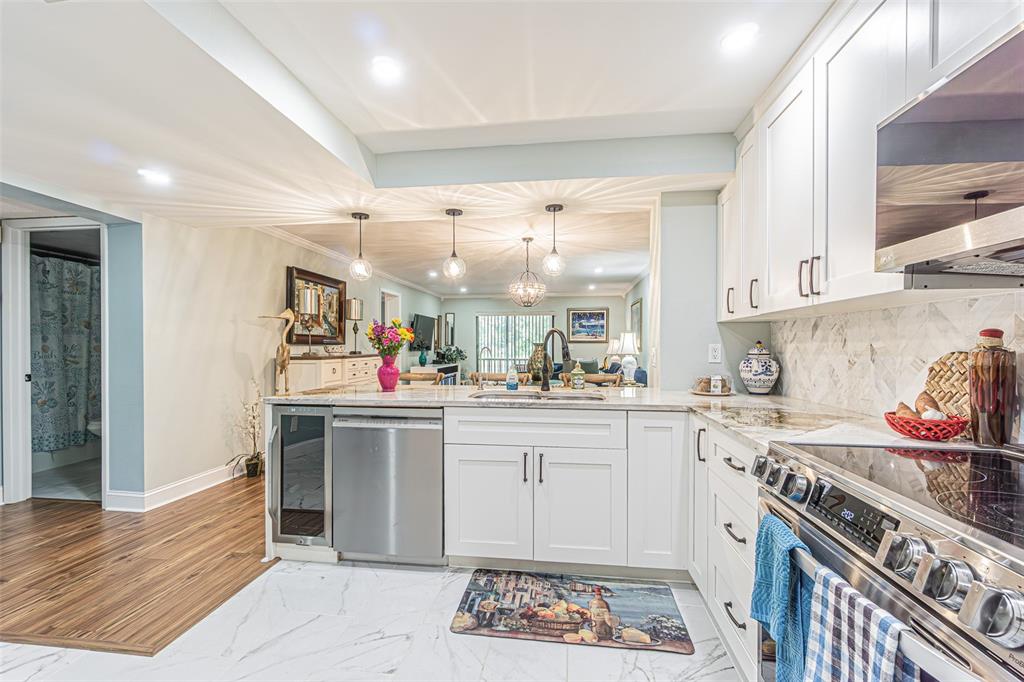 A modern kitchen with white cabinets, stainless steel appliances, and marble-look flooring — 3505 TARPON WOODS BOULEVARD UNIT G405, PALM HARBOR, FL