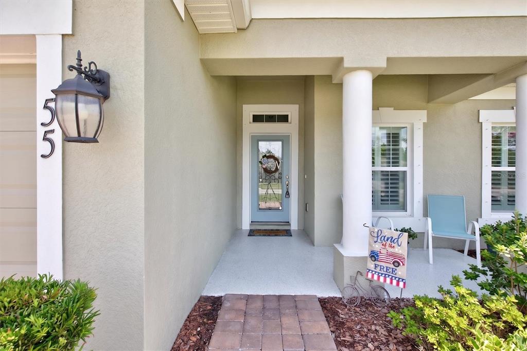 The exterior front entrance features a light blue door, a white column, and a porch — 55 HUNTINGTON PLACE, ORMOND BEACH, FL