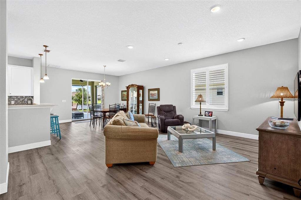 An open-concept living and dining area features light gray walls, wood-look flooring, and a patio — 55 HUNTINGTON PLACE, ORMOND BEACH, FL