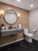A modern bathroom features a floating vanity, a round mirror, and wood-look wall tiles — 2511 W MLK BOULEVARD, TAMPA, FL
