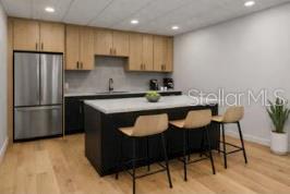 A modern kitchen features light wood cabinets, a dark island with bar stools, and stainless appliances — 2511 W MLK BOULEVARD, TAMPA, FL