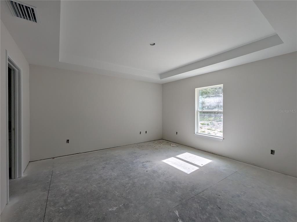An empty room features a tray ceiling, a single window, and unfinished concrete flooring — 8943 N TROJAN DRIVE S, CITRUS SPRINGS, FL