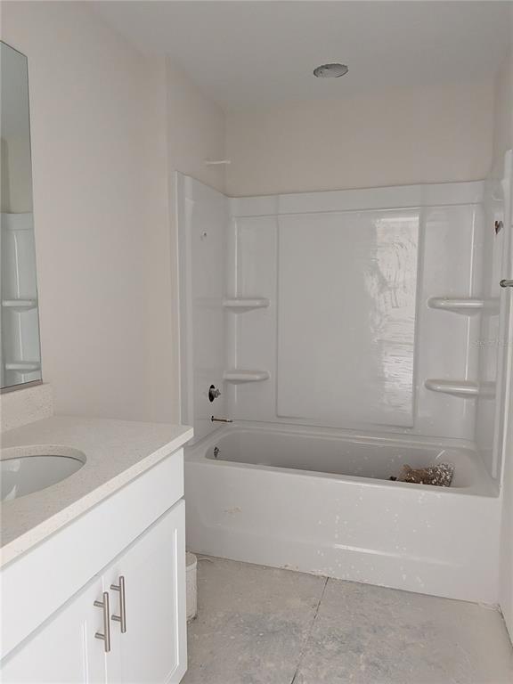 A bathroom featuring a white vanity with a stone countertop and a white tub-shower combo — 8943 N TROJAN DRIVE S, CITRUS SPRINGS, FL