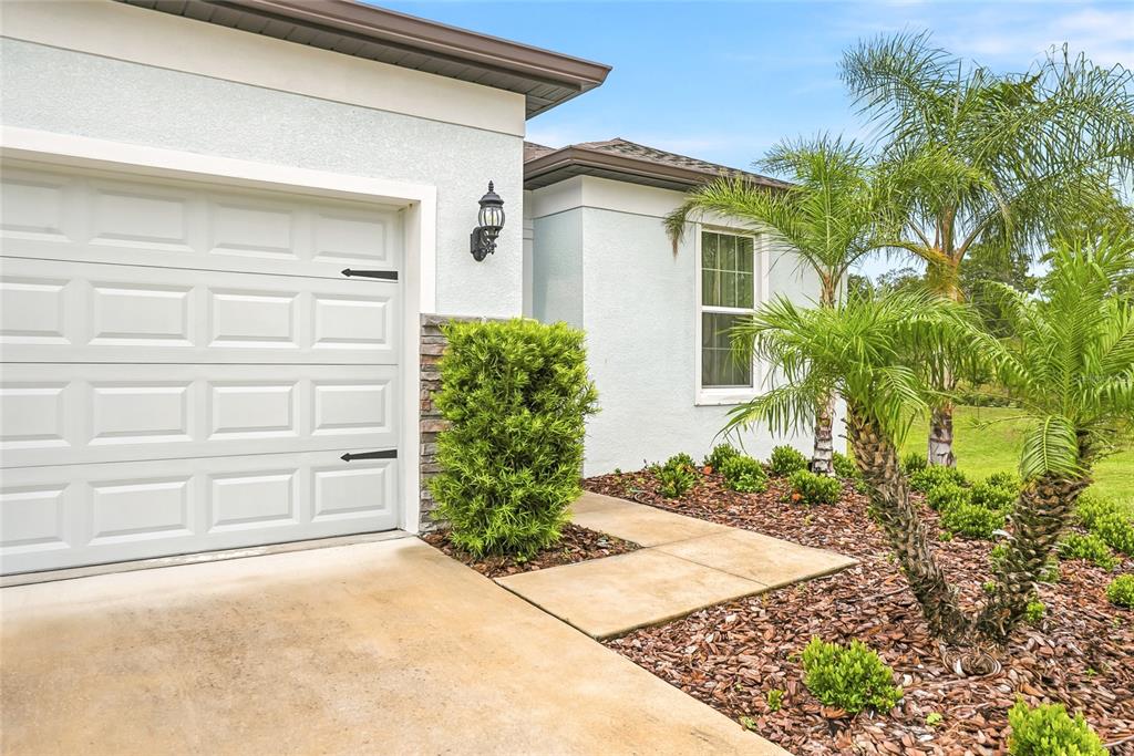 The exterior of a house features a white garage door, a window, and landscaping — 4678 DOVER BLUFF COURT, VALRICO, FL
