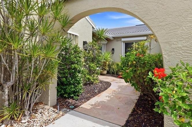 A stone walkway leads through an arched entryway toward the front door of a house — 2521 W MARION AVENUE UNIT 311, PUNTA GORDA, FL