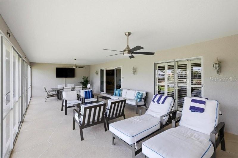 A covered patio features outdoor furniture, ceiling fans, and a television on a light wall — 2521 W MARION AVENUE UNIT 311, PUNTA GORDA, FL