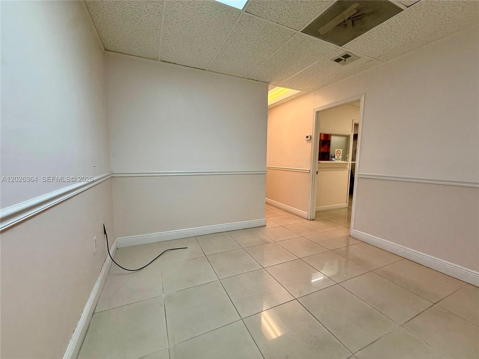 An empty office space features beige tile flooring, white walls with chair rails, and drop ceilings — 8370 W Flagler St # 120, Miami FL 33144, MIAMI, FL