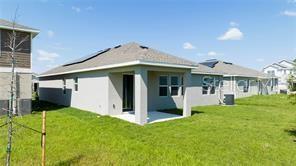 The exterior rear view of a single-story house features a covered patio and grassy yard — 1163 JAMES PAUL ROAD, DAVENPORT, FL