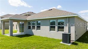 The exterior rear view of a house features a covered patio and an air conditioning unit — 1163 JAMES PAUL ROAD, DAVENPORT, FL