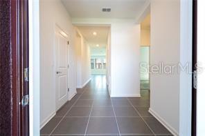 A view from a doorway looking down a hallway with tile flooring and white walls — 1163 JAMES PAUL ROAD, DAVENPORT, FL