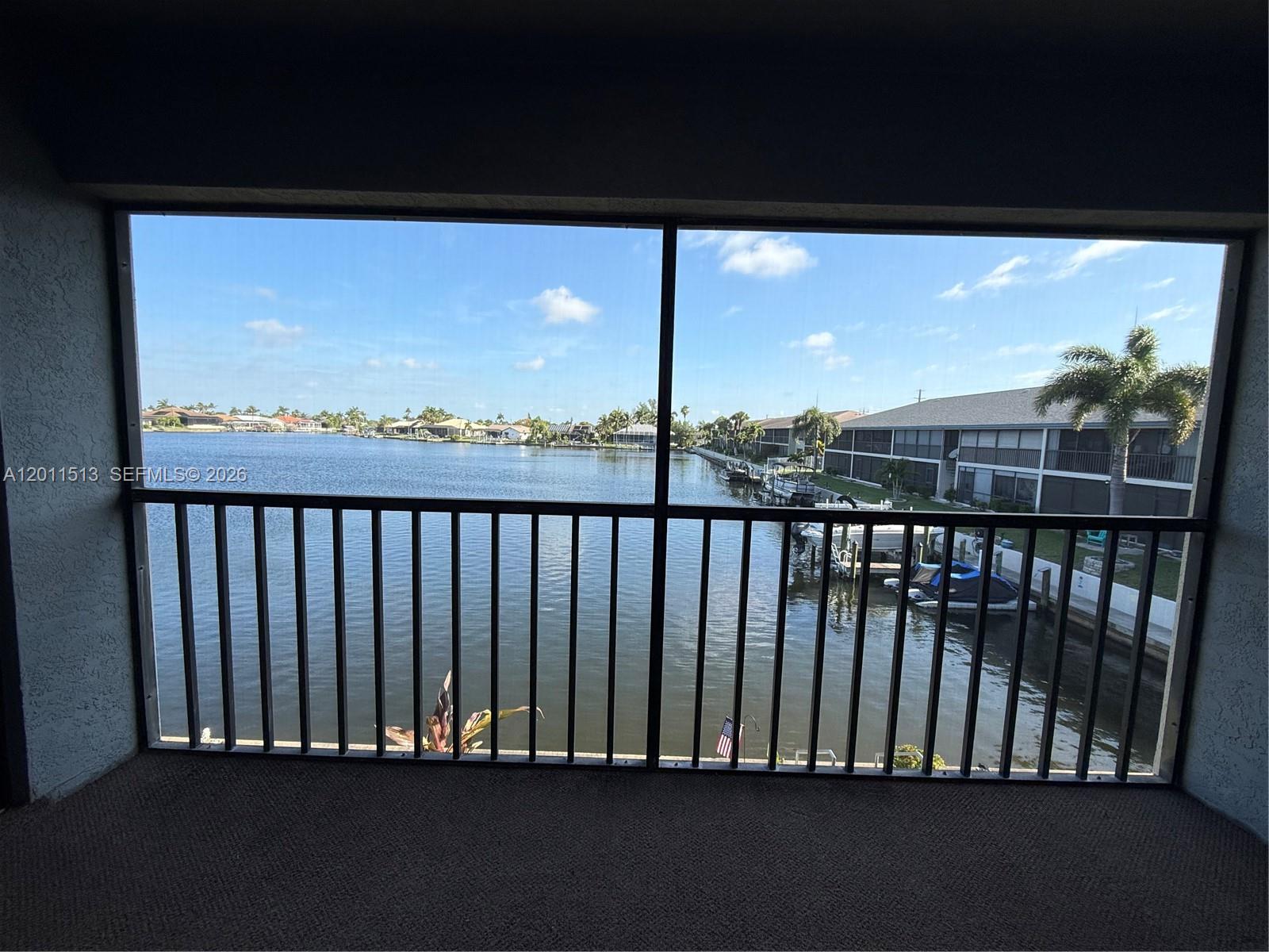 A screened-in balcony overlooks a canal with docked boats and residential buildings — 123 SW 47TH TER # 201, Cape Coral FL 33914, CAPE CORAL, FL