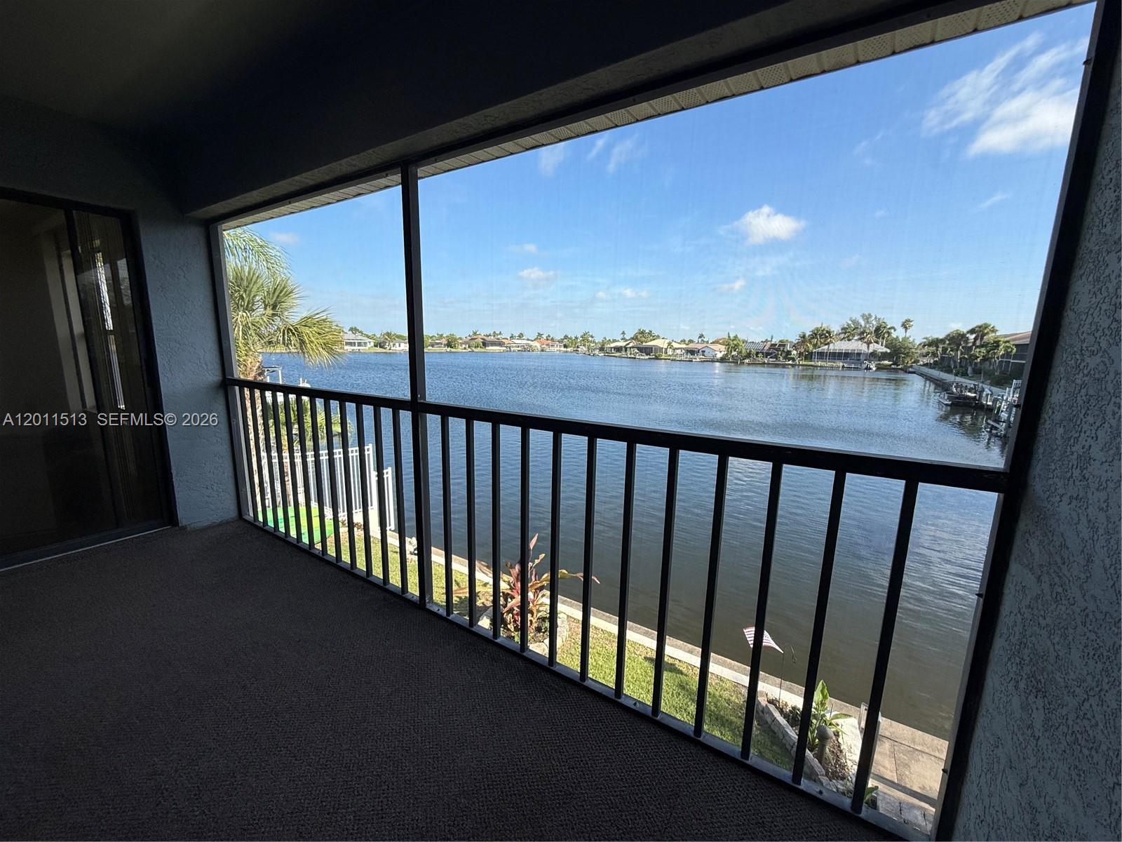 A screened-in balcony overlooks a lake with houses along the distant shoreline — 123 SW 47TH TER # 201, Cape Coral FL 33914, CAPE CORAL, FL