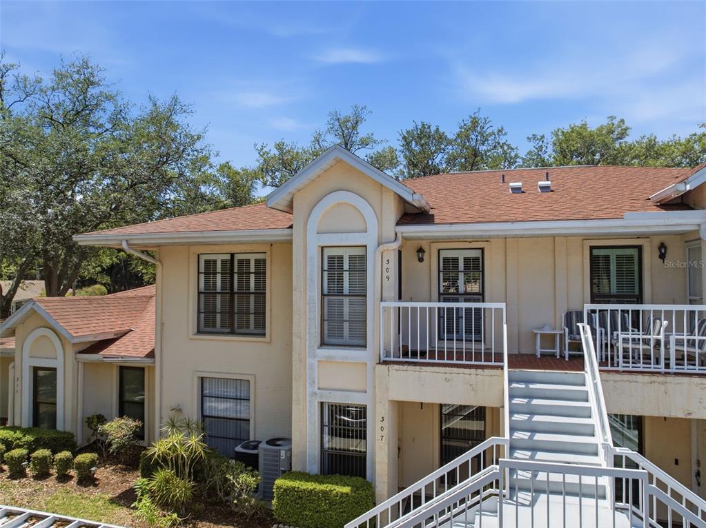 An exterior view of a two-story apartment building with beige stucco walls and stairs — 309 KNOTTWOOD COURT UNIT 309, SUN CITY CENTER, FL