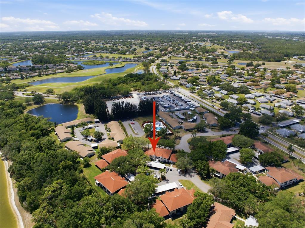 An aerial view shows a residential complex with red-tiled roofs and a red arrow pointing down — 309 KNOTTWOOD COURT UNIT 309, SUN CITY CENTER, FL