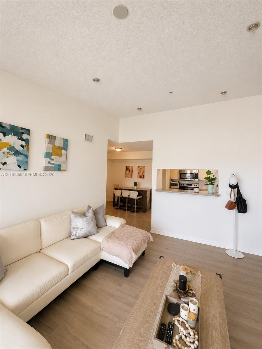 A living room with a white sectional sofa, coffee table, and a pass-through kitchen window — 2240 E Preserve Way # 308, Miramar FL 33025, MIRAMAR, FL