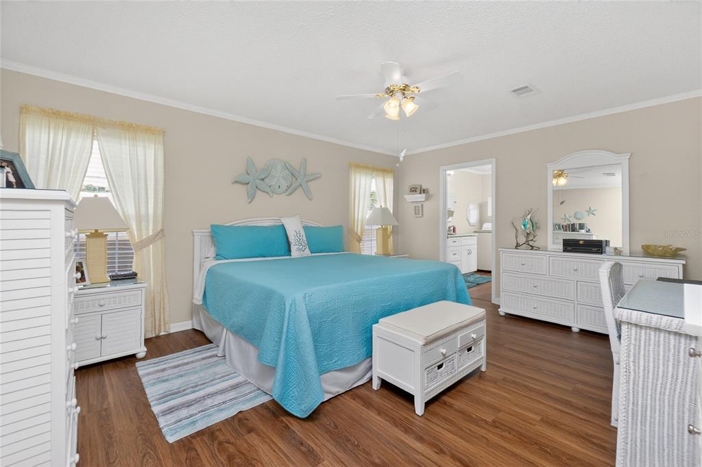A bedroom features a blue bed, white furniture, wood-look flooring, and a ceiling fan — 10303 BURNT STORE ROAD UNIT 233, PUNTA GORDA, FL