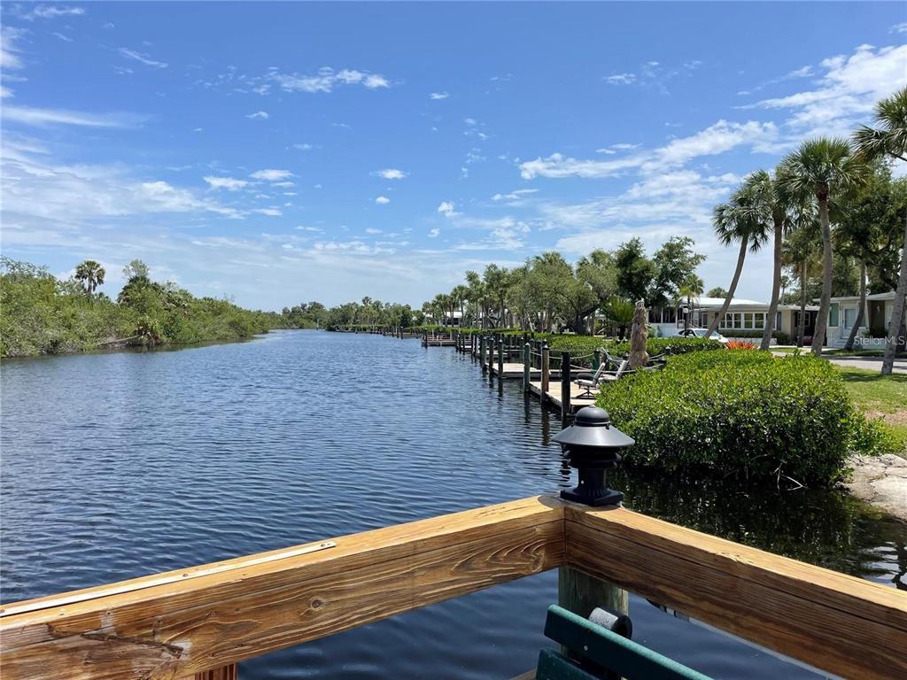 A wooden deck overlooks a narrow canal lined with boat docks and palm trees — 10303 BURNT STORE ROAD UNIT 233, PUNTA GORDA, FL