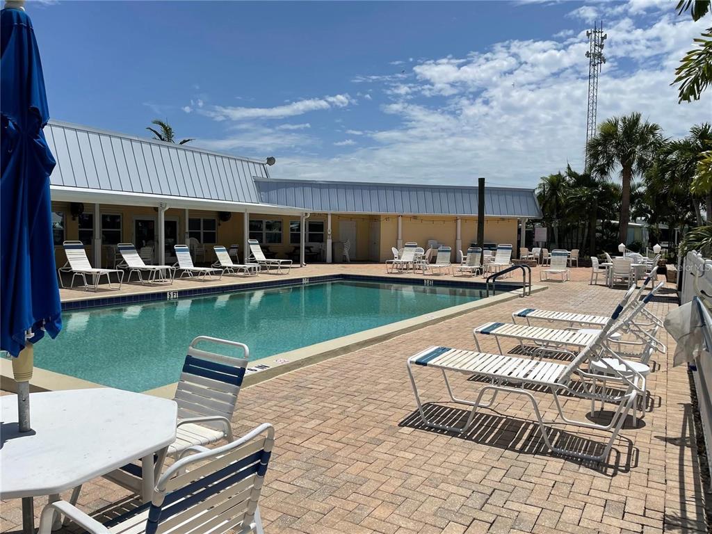 A swimming pool with lounge chairs on a brick patio beside a single-story building — 10303 BURNT STORE ROAD UNIT 233, PUNTA GORDA, FL