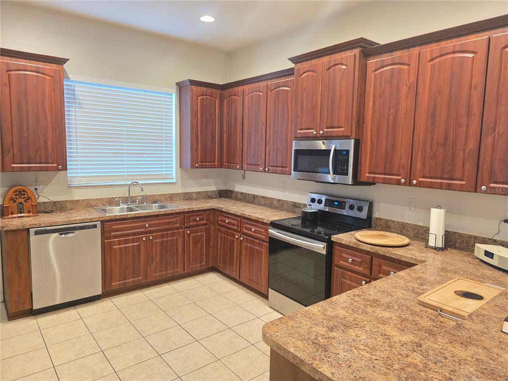 A kitchen features wood cabinets, laminate countertops, a stainless steel dishwasher, and a built-in microwave — 4266 HIGH RIDGE AVENUE, SPRING HILL, FL