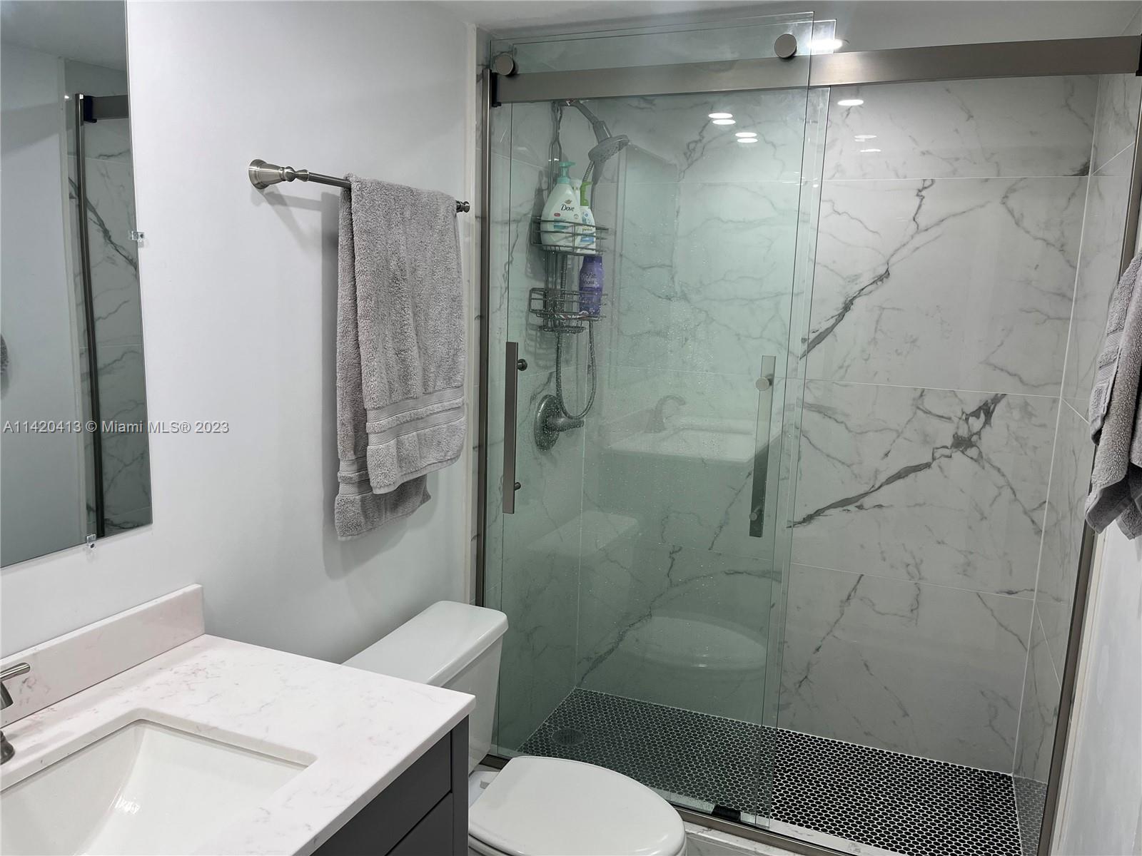 A bathroom features a marble-tiled walk-in shower, a vanity with a stone countertop, and a toilet — 2030 S Ocean Dr # 1602, Hallandale Beach FL 33009, HALLANDALE BEACH, FL
