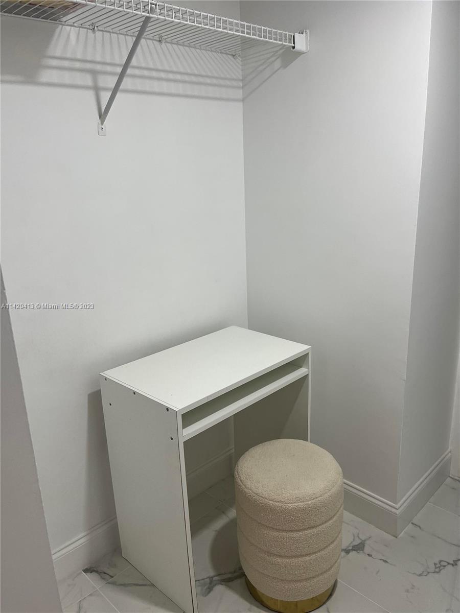 A small white desk and a round textured stool sit inside a walk-in closet — 2030 S Ocean Dr # 1602, Hallandale Beach FL 33009, HALLANDALE BEACH, FL