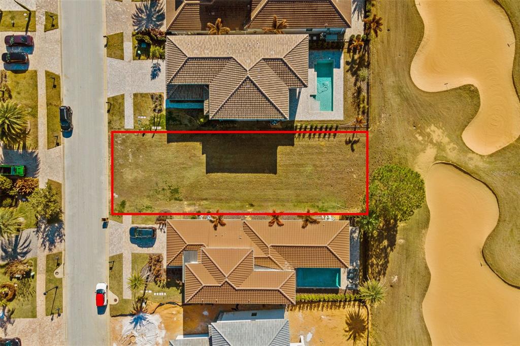 An aerial view shows a vacant rectangular residential lot situated between two houses and a golf course — 15938 VETTA DRIVE, BELLA COLLINA, FL