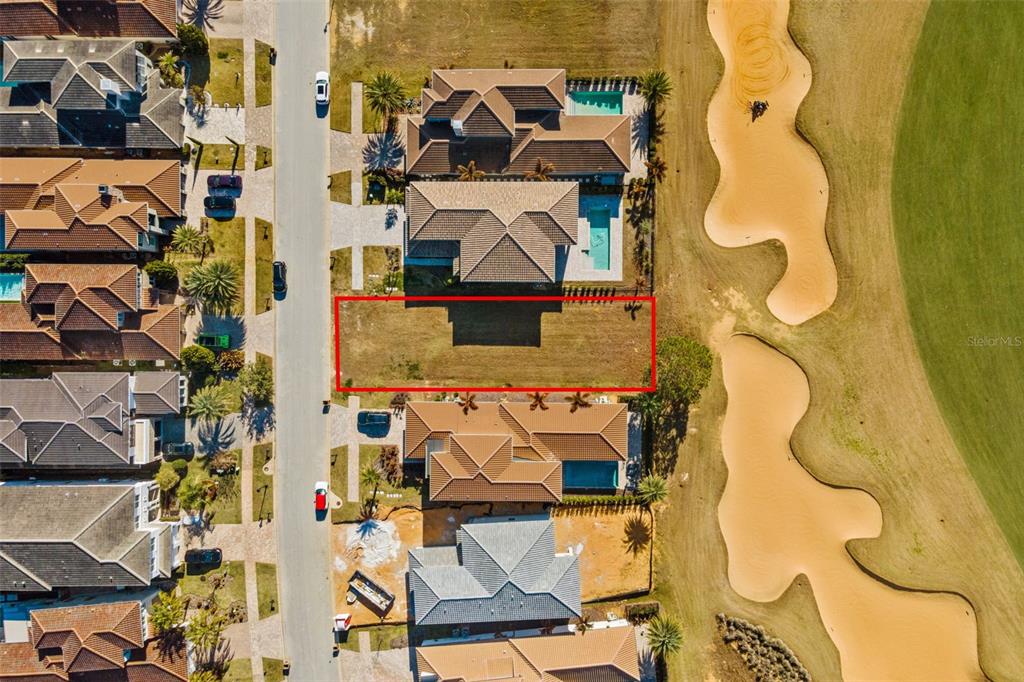 An aerial view shows a vacant rectangular residential lot situated between two houses and a golf course — 15938 VETTA DRIVE, BELLA COLLINA, FL