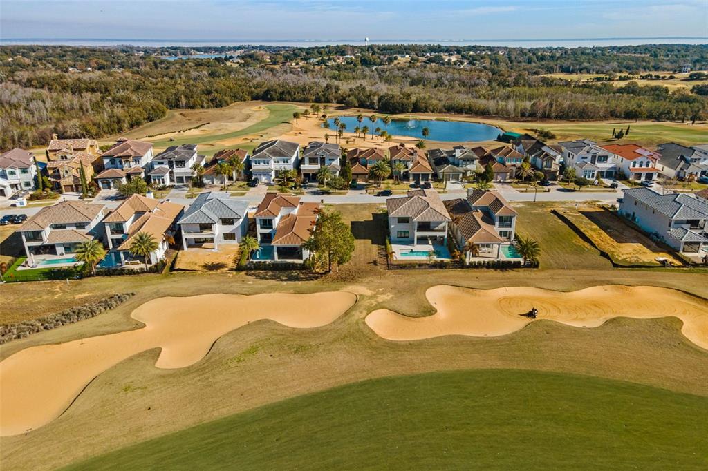 An aerial view shows a row of houses overlooking a golf course with sand bunkers — 15938 VETTA DRIVE, BELLA COLLINA, FL