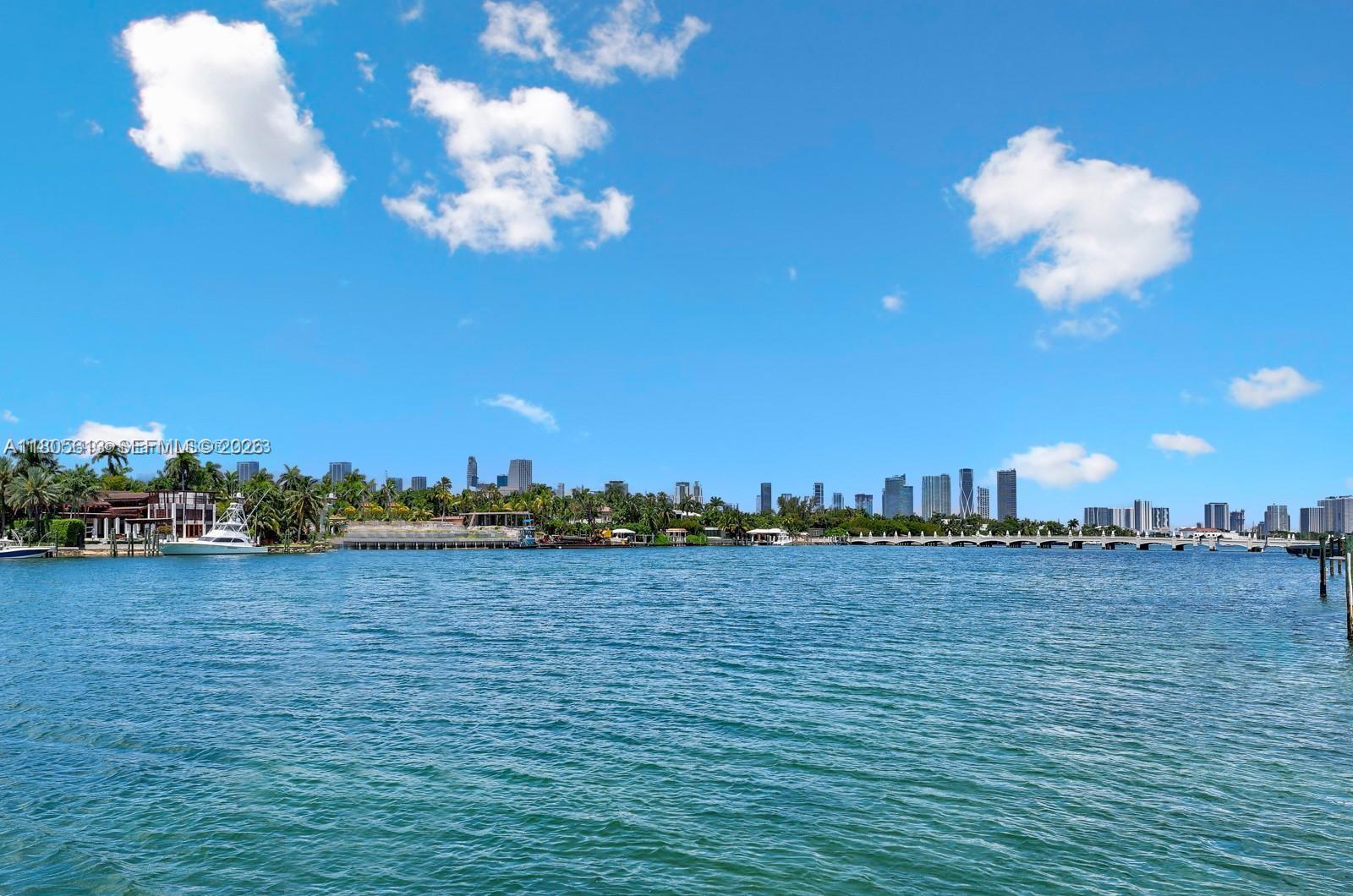 A patio with a dining table, swimming pool, and lounge chairs overlooks a waterfront dock — 56 S Hibiscus Dr, Miami Beach FL 33139, MIAMI BEACH, FL