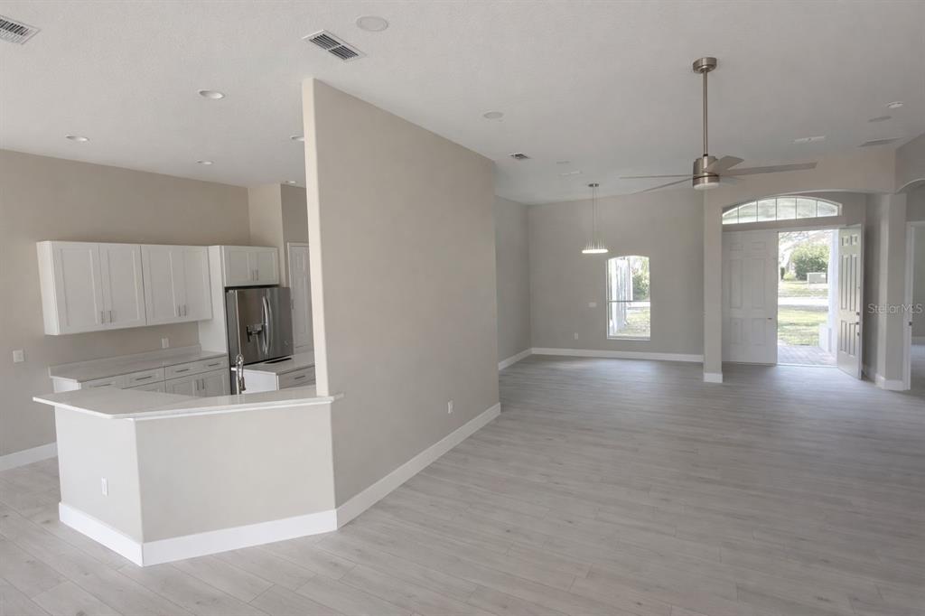 An open-concept kitchen with white cabinets and a breakfast bar overlooks a spacious living area — 3504 VALLEYVIEW DRIVE, KISSIMMEE, FL
