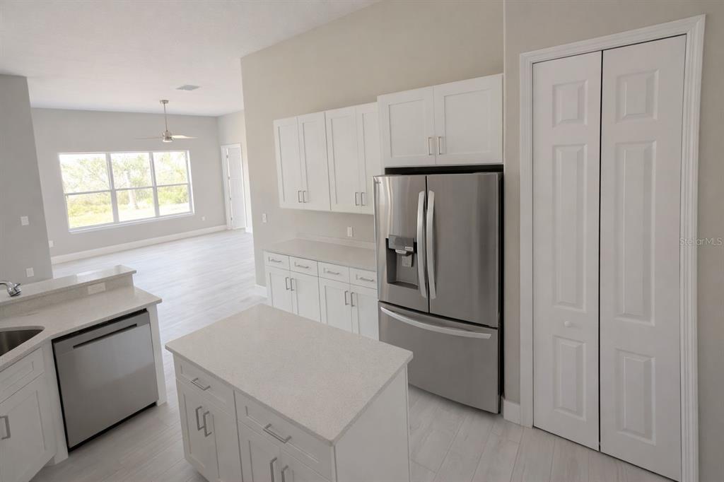 A kitchen features white cabinets, stainless steel appliances, a center island, and light-colored flooring — 3504 VALLEYVIEW DRIVE, KISSIMMEE, FL