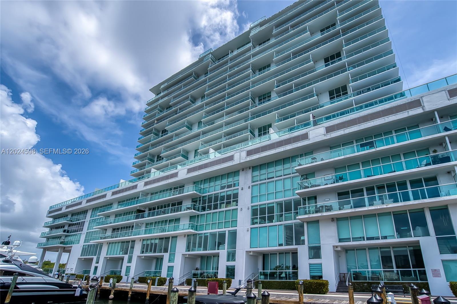A low-angle view shows the exterior of a modern multi-story residential building with glass balconies — 400 Sunny Isles Blvd # 1202, Sunny Isles Beach FL 33160, SUNNY ISLES BEACH, FL