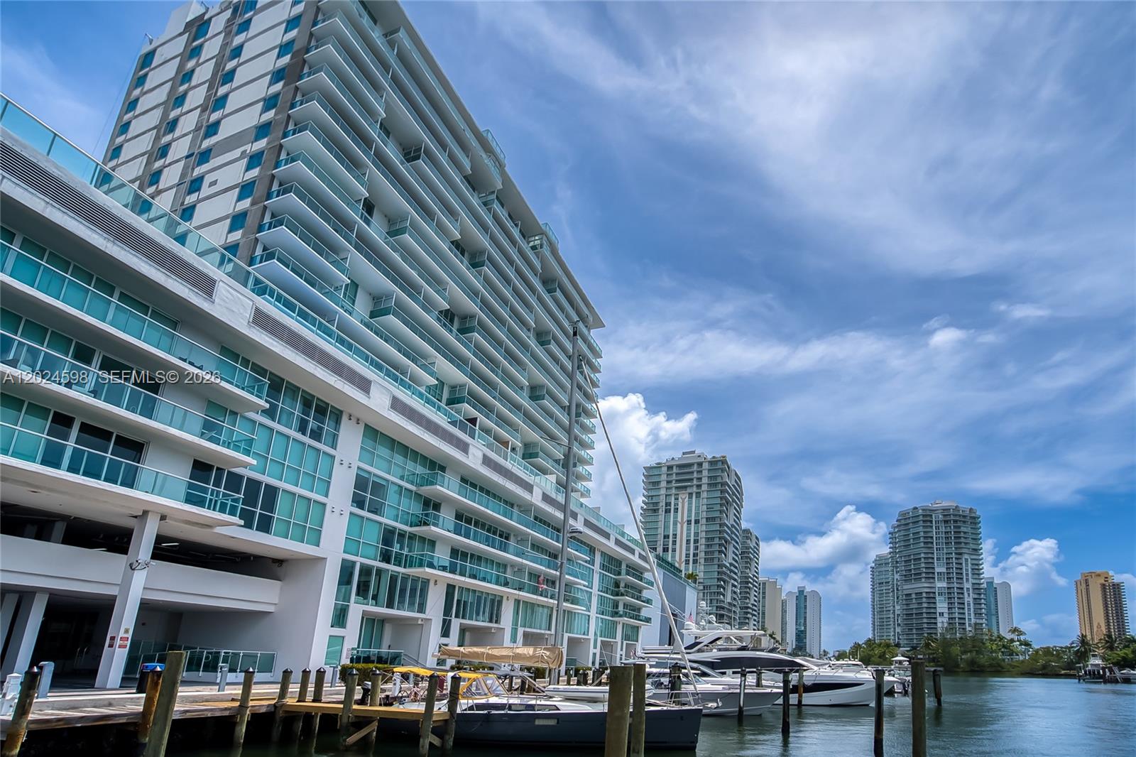 A modern high-rise residential building stands beside a marina with docked boats and yachts — 400 Sunny Isles Blvd # 1202, Sunny Isles Beach FL 33160, SUNNY ISLES BEACH, FL
