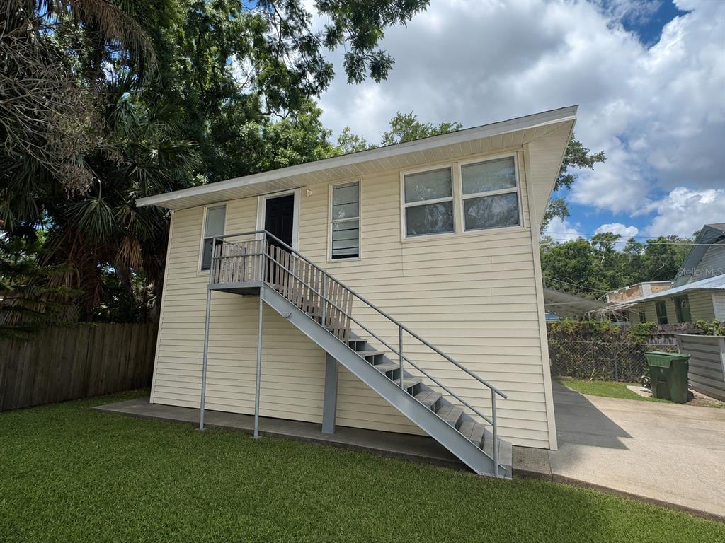A two-story white stucco building features a yellow front door and a metal privacy screen — 514 AVENUE C NE, WINTER HAVEN, FL