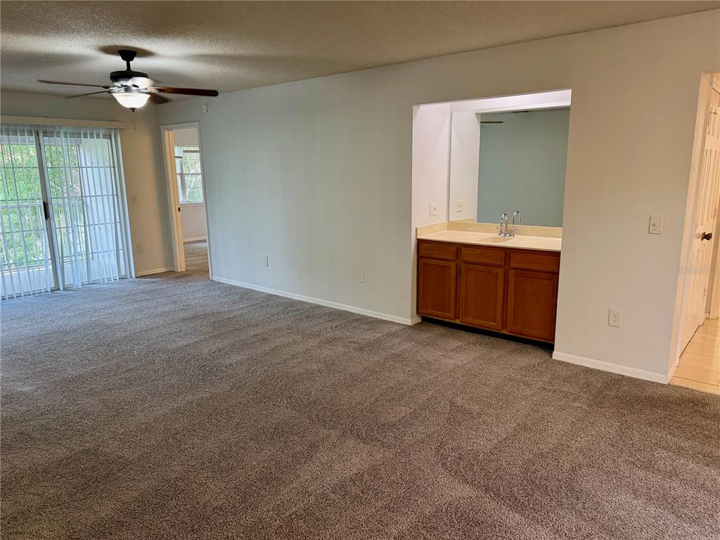 A carpeted bedroom features a ceiling fan, sliding glass doors, and an open vanity area — 4316 CLUBSIDE DRIVE UNIT 4316, LONGWOOD, FL