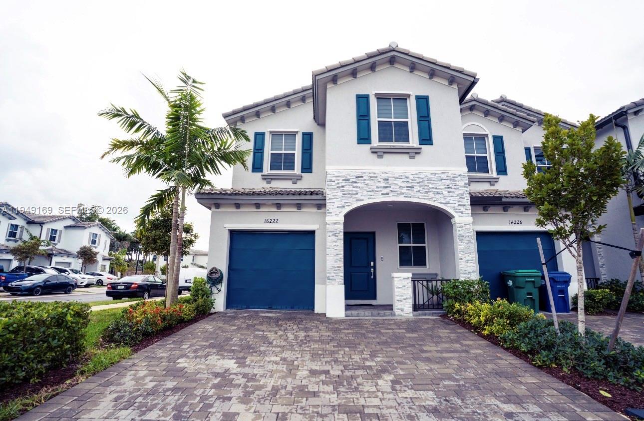 A two-story house features a stone-accented entryway, blue garage doors, and blue window shutters — 16222 SW 290th Ter, Homestead FL 33033, HOMESTEAD, FL